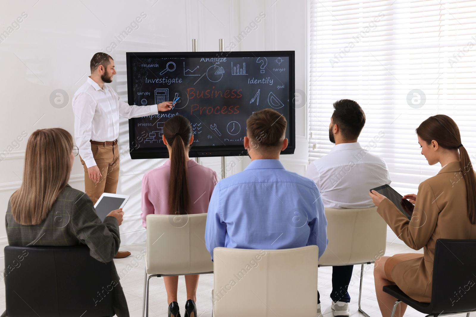 Photo of Business trainer using interactive board in meeting room during presentation