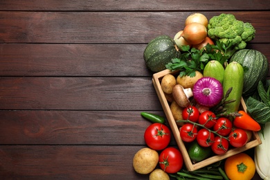 Fresh vegetables in crate on wooden table, flat lay. Space for text