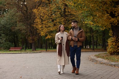 Photo of Romantic young couple spending time together in autumn park, space for text