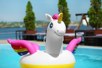 Photo of Funny inflatable unicorn ring floating in swimming pool on sunny day, outdoors