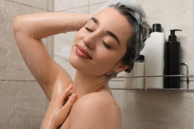 Photo of Beautiful woman washing hair with shampoo in shower