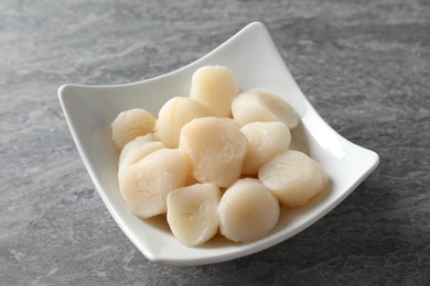 Photo of Fresh raw scallops in bowl on grey table