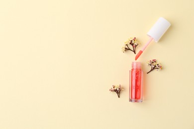 Photo of Bright lip gloss, applicator and flowers on yellow background, top view. Space for text