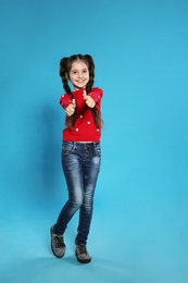 Full length portrait of little girl posing on color background