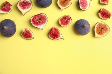 Delicious ripe figs on yellow background, flat lay. Space for text