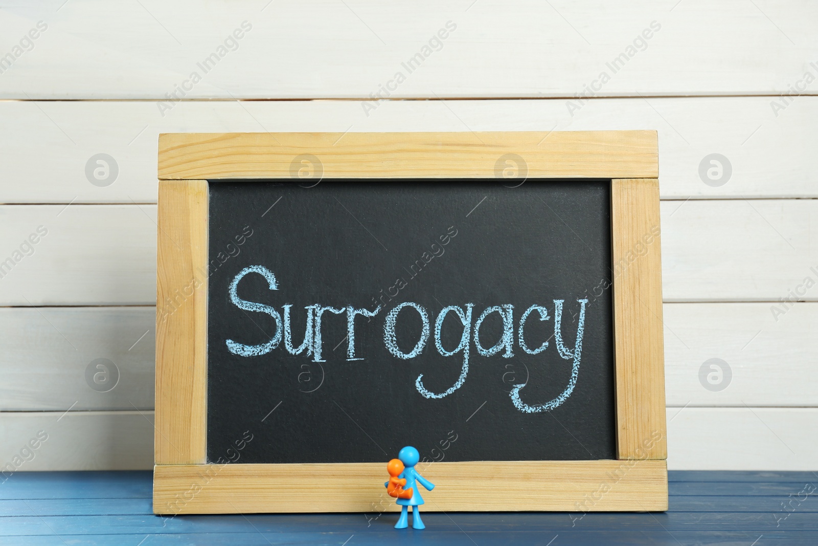 Photo of MYKOLAIV, UKRAINE - JANUARY 04, 2022: Small blackboard with word Surrogacy and colorful human figures on blue wooden table