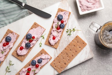 Tasty cracker sandwiches with cream cheese, blueberries, red currants, thyme and cup of coffee on grey table, flat lay