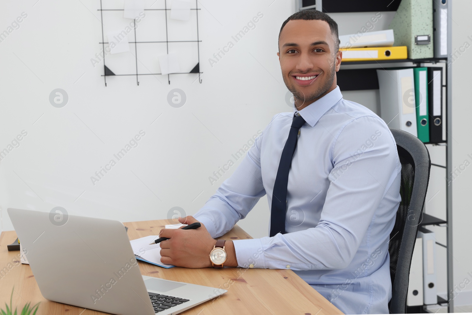 Photo of Happy young intern working at table in modern office