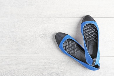 Pair of female shoes on wooden background, top view