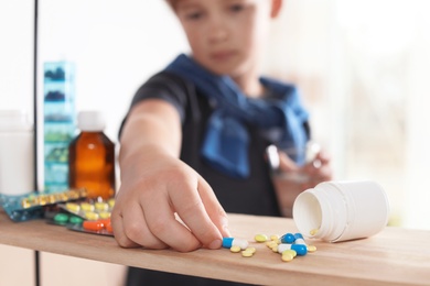 Photo of Little child taking pills from shelf at home, closeup. Danger of medicament intoxication