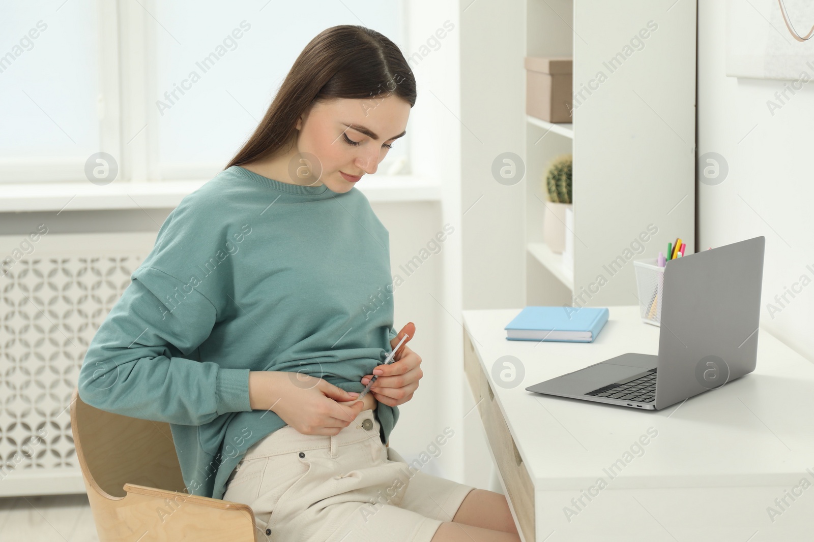 Photo of Diabetes. Woman making insulin injection into her belly at table indoors