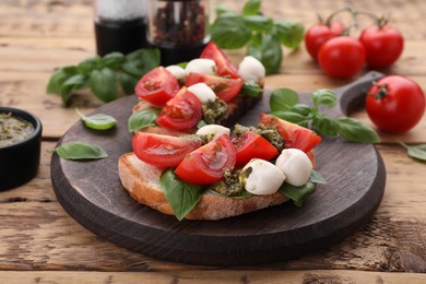 Photo of Delicious Caprese sandwiches with mozzarella, tomatoes, basil and pesto sauce on wooden table, closeup