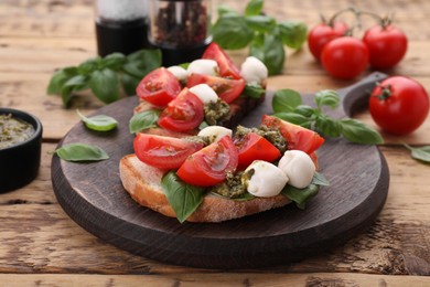 Delicious Caprese sandwiches with mozzarella, tomatoes, basil and pesto sauce on wooden table, closeup