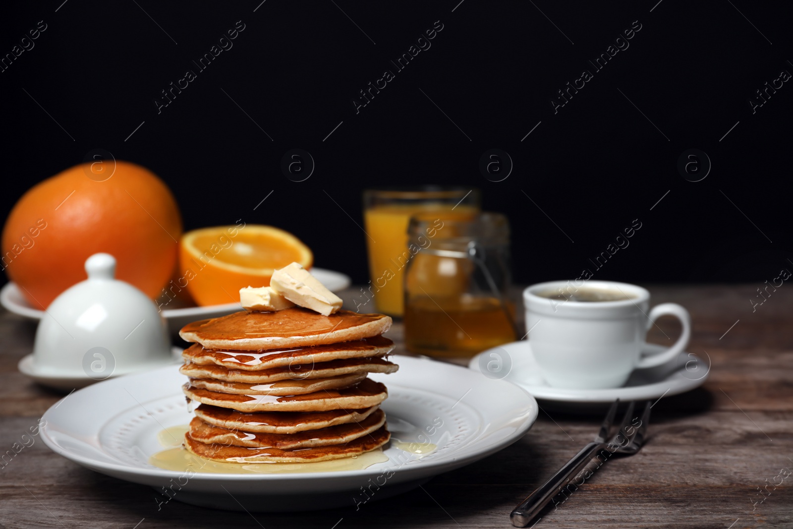 Photo of Delicious pancakes with butter and honey served for breakfast on table