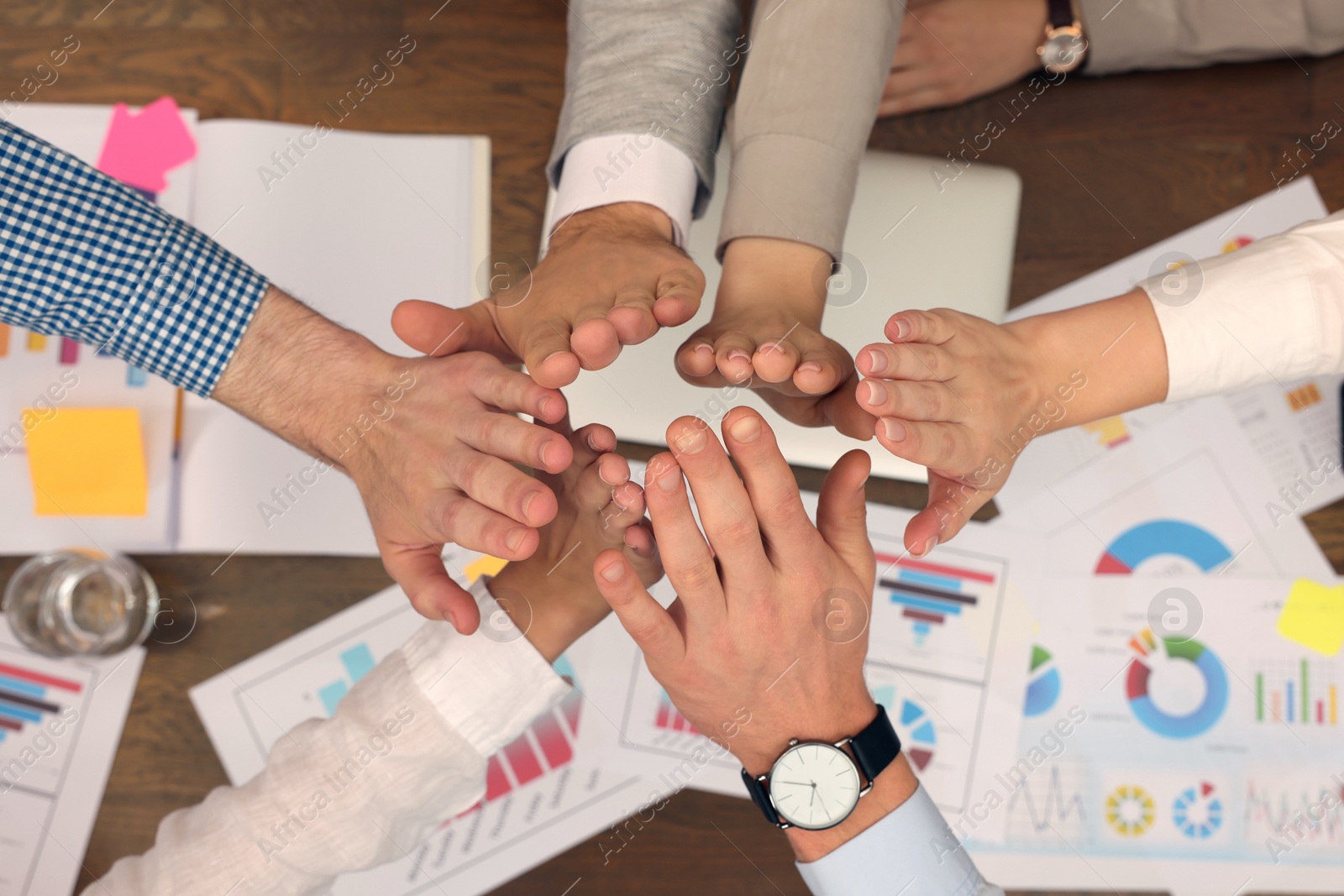 Photo of Office employees joining hands at work, top view