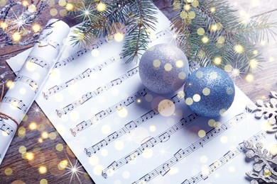 Composition with Christmas decorations and music sheets on wooden background. Bokeh effect