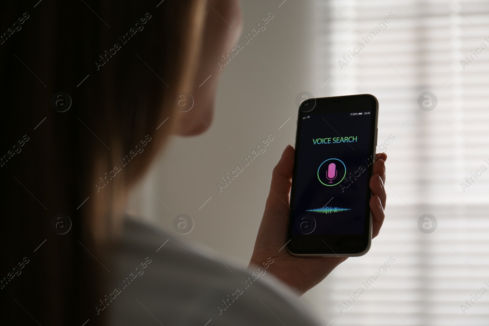 Photo of Woman using voice search on smartphone indoors, closeup