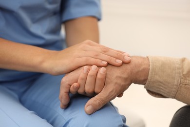 Photo of Nurse supporting elderly patient indoors, closeup view