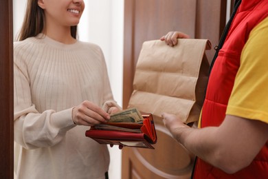 Photo of Woman giving tips to deliveryman indoors, closeup