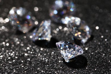 Photo of Many beautiful diamonds on dark shiny background, closeup