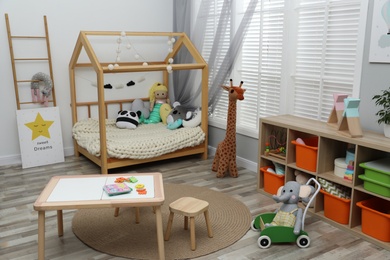 Photo of Cute child's room interior with toys and wooden furniture