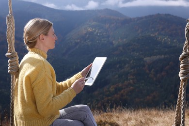 Photo of Young woman drawing with graphic tablet in mountains