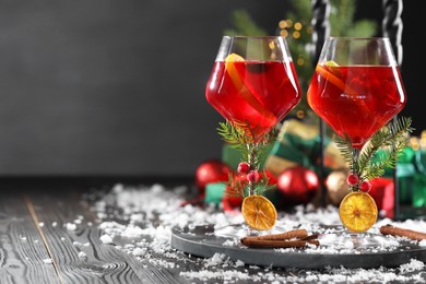 Photo of Christmas Sangria cocktail in glasses and snow on dark wooden table, space for text