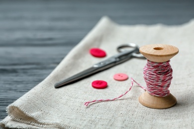 Composition with thread and sewing accessories on wooden background