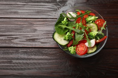 Photo of Tasty fresh vegetarian salad on dark wooden table, top view. Space for text