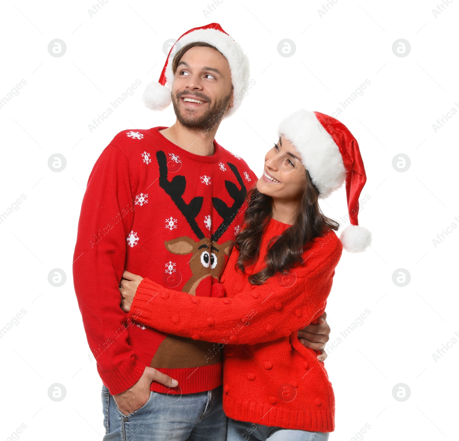 Photo of Young couple in Christmas sweaters and hats on white background