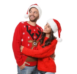 Young couple in Christmas sweaters and hats on white background