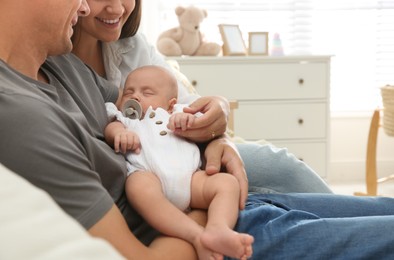 Photo of Happy couple holding their sleeping baby at home, closeup