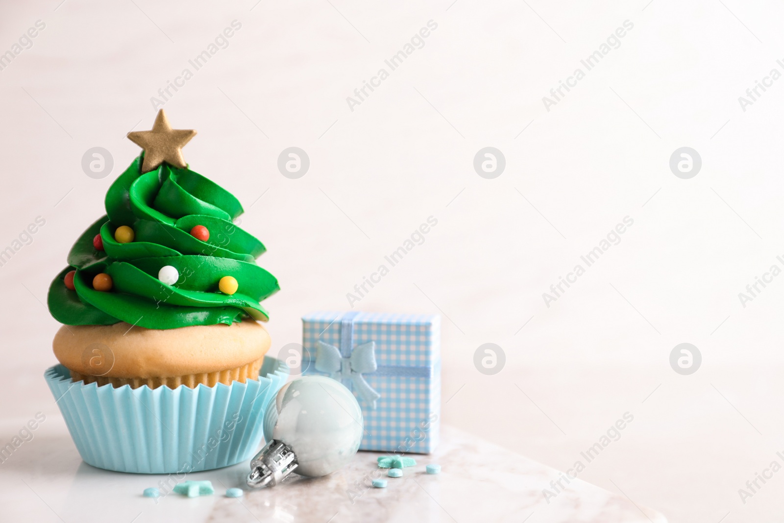 Photo of Christmas tree shaped cupcake and decor on table. Space for text