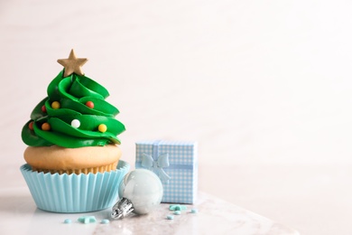 Photo of Christmas tree shaped cupcake and decor on table. Space for text