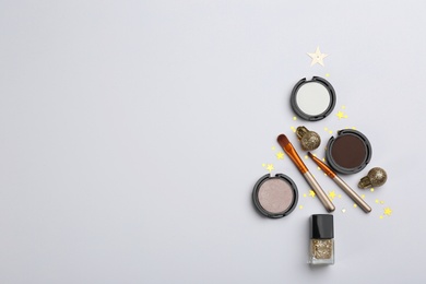 Photo of Christmas tree shape of decorative cosmetic products on light background, flat lay, space for text.  Winter care