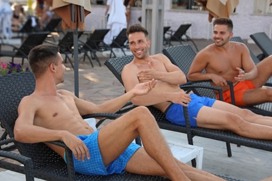 Photo of Happy young friends relaxing on deck chairs outdoors