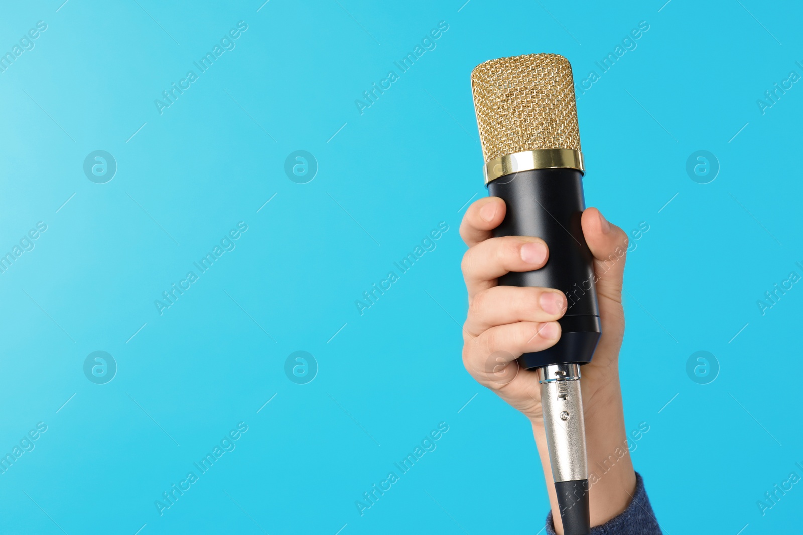 Photo of Child holding microphone on color background, closeup of hand. Space for text