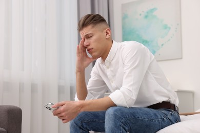 Photo of Overwhelmed man sitting on bed at home