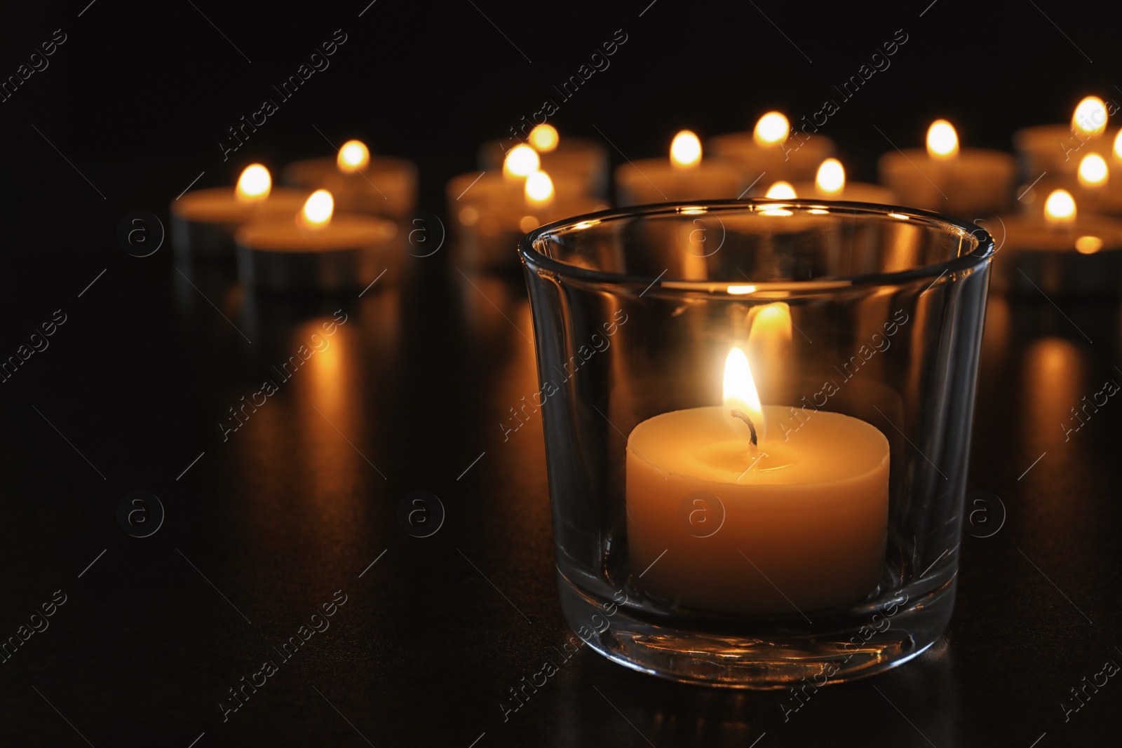 Photo of Wax candle burning on table in darkness, closeup