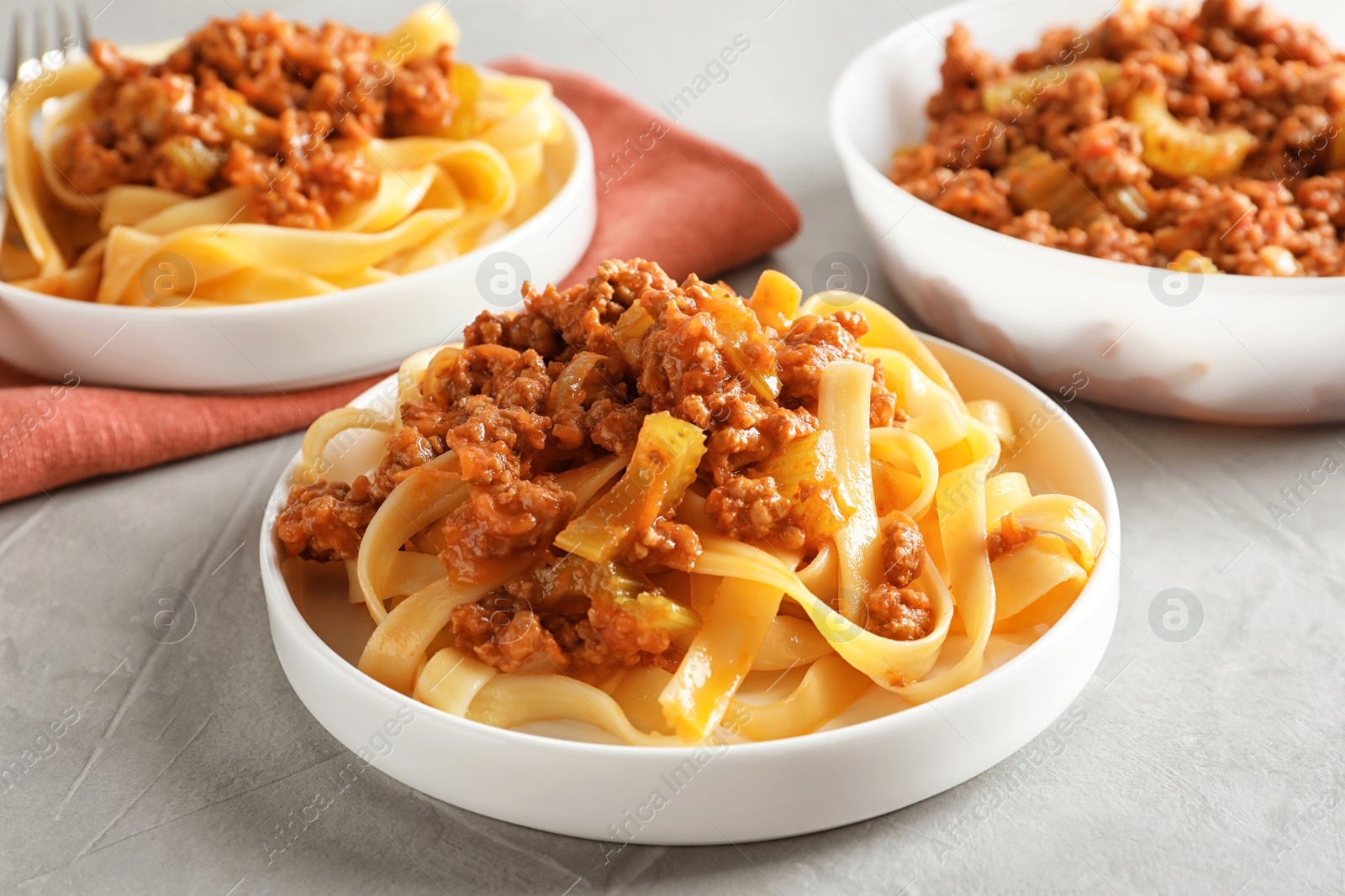 Photo of Plates with delicious pasta bolognese on grey background