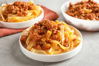Plates with delicious pasta bolognese on grey background