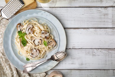 Photo of Delicious pasta with mushrooms and cheese served on white wooden table, flat lay. Space for text