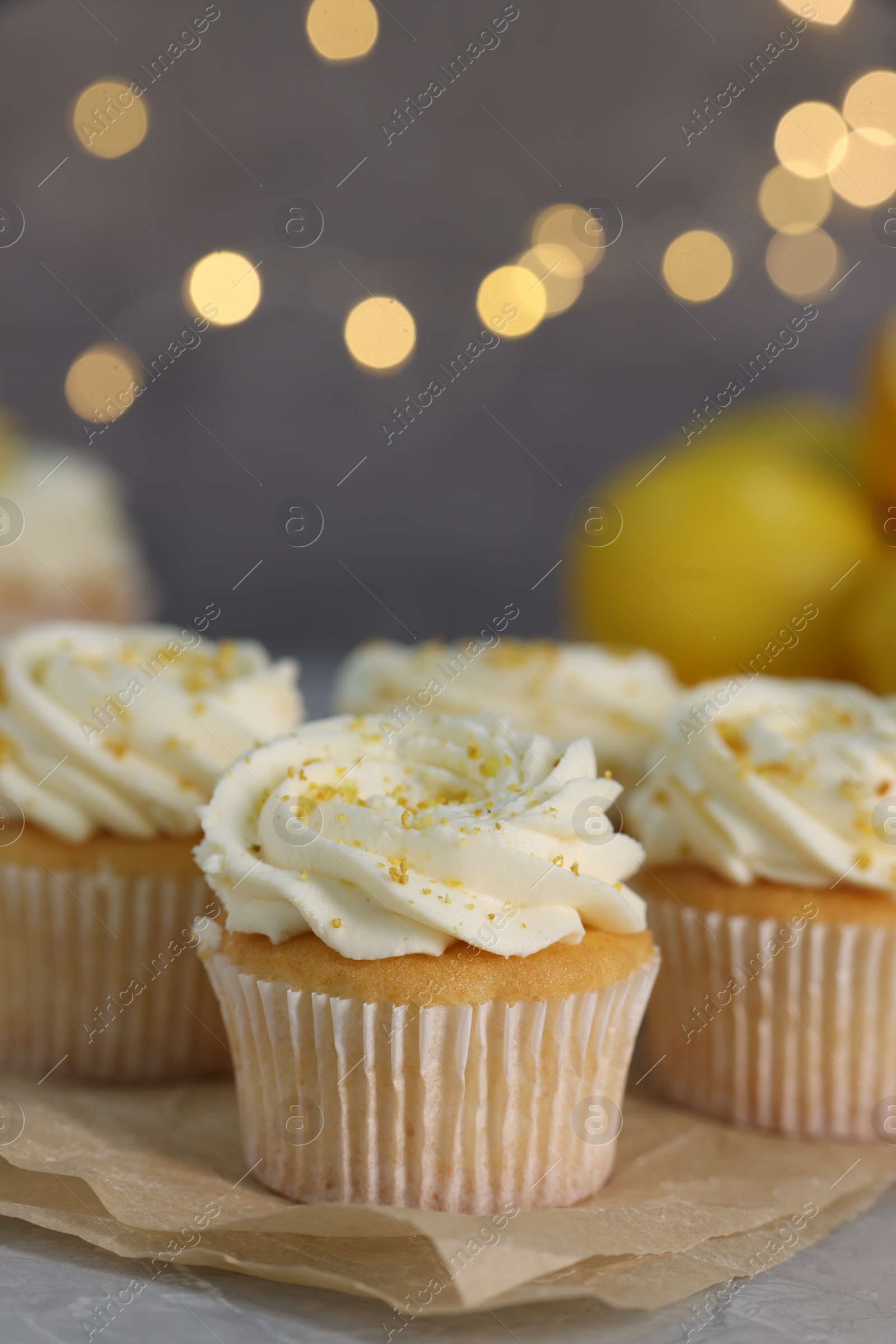 Photo of Delicious cupcakes with white cream and lemon zest on table, closeup. Space for text