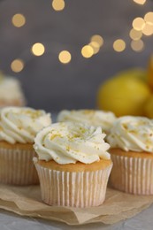 Photo of Delicious cupcakes with white cream and lemon zest on table, closeup. Space for text