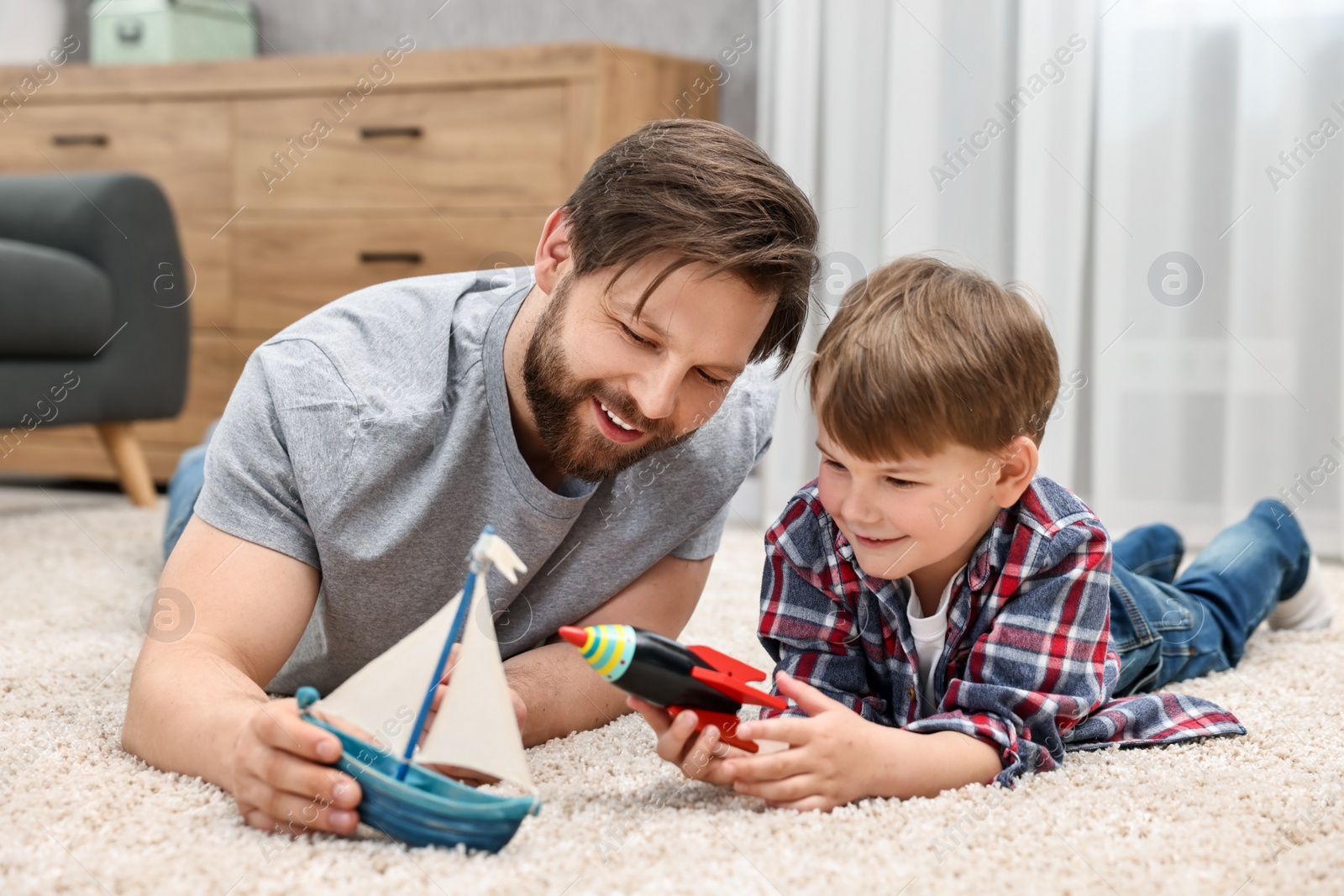 Photo of Happy dad and son playing toys together at home