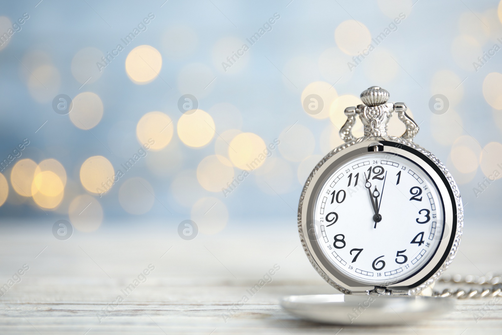 Photo of Pocket watch on table against blurred lights, space for text. New Year countdown