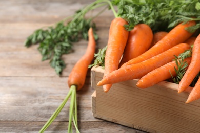 Photo of Crate of fresh carrots on wooden background, closeup. Space for text