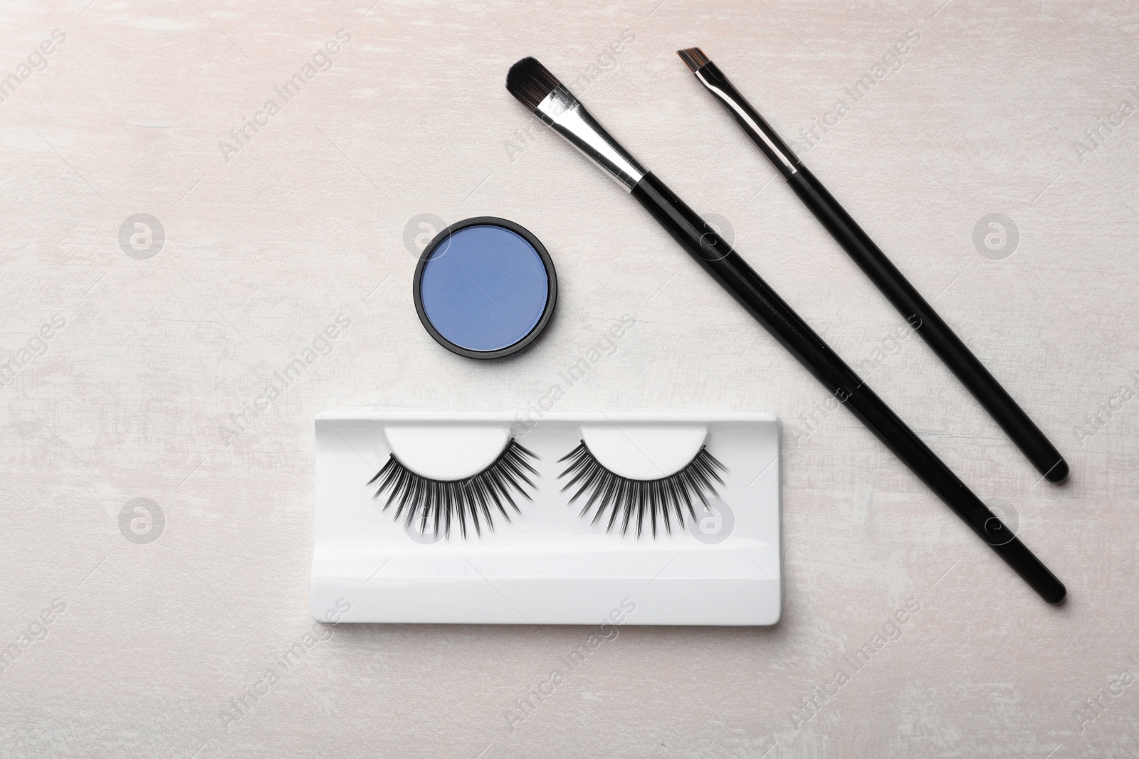 Photo of Artificial eyelashes and accessories on light background, flat lay