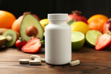 Photo of Vitamin pills, bottle and fresh fruits on wooden table