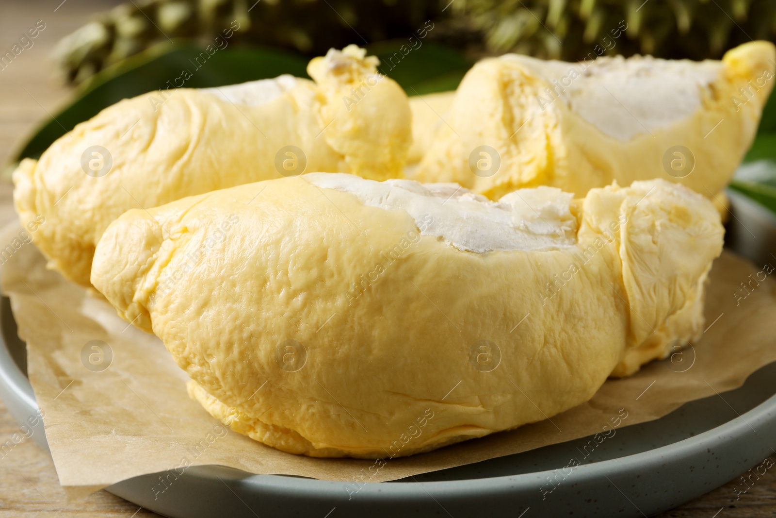 Photo of Plate with fresh ripe durian on wooden table, closeup